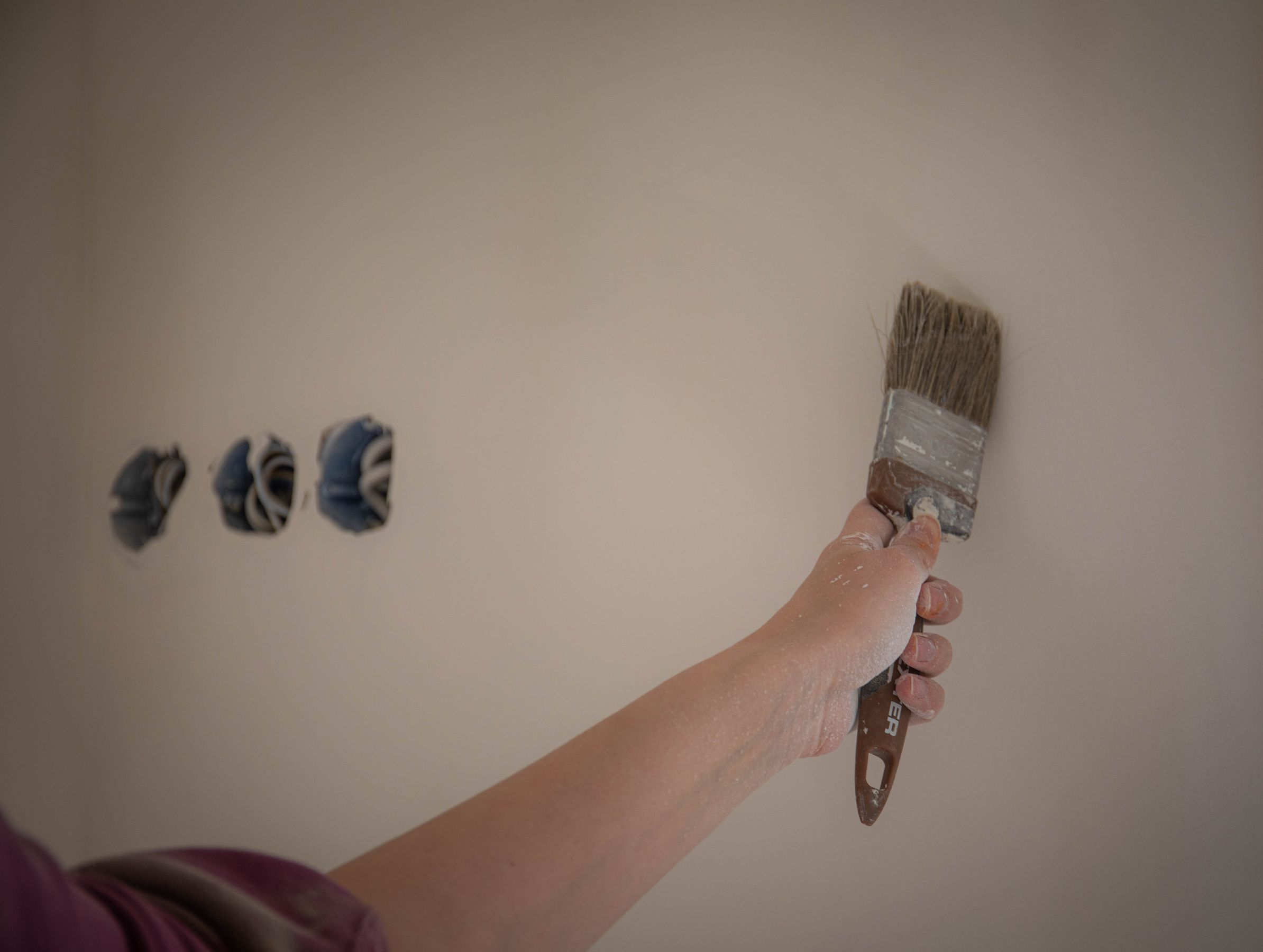 A person painting an interior wall with a brush