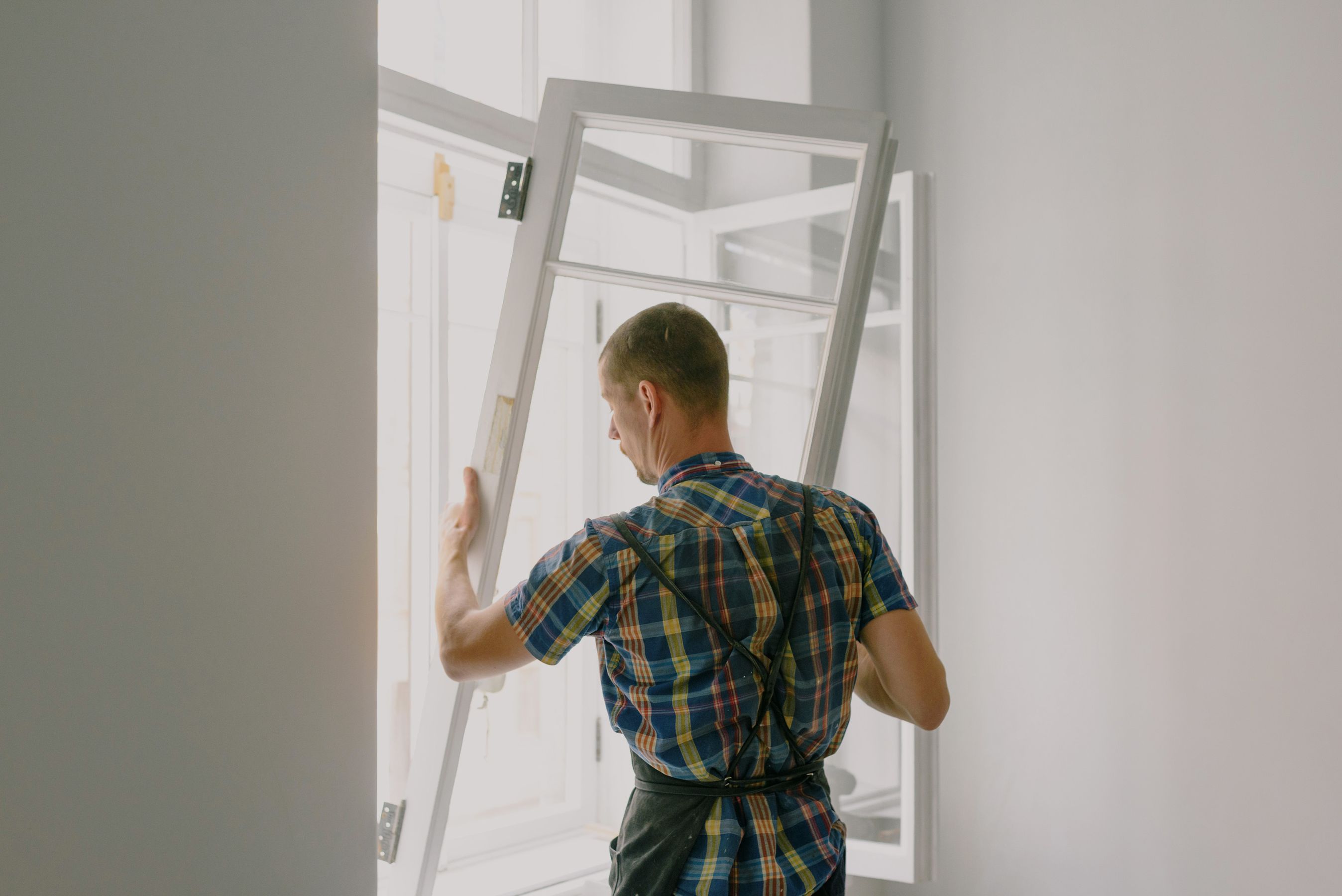 A worker in an apron mounting a window at a residential home
